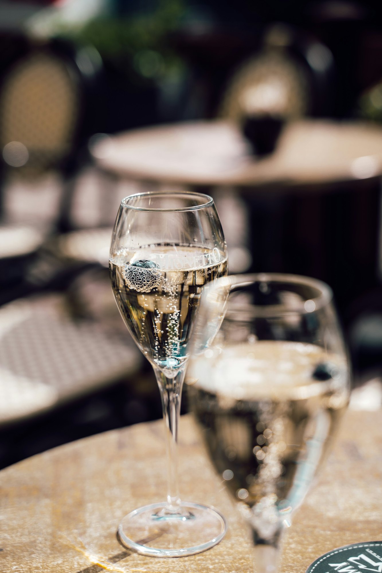 Two glasses of sparkling wine on a sunlit outdoor table